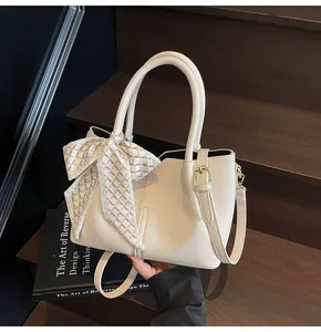 Détail du sac seau beige avec texture litchi et foulard en soie sur la poignée