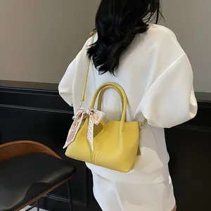 Sac seau minimaliste en cuir jaune vif avec foulard décoratif et bandoulière réglable