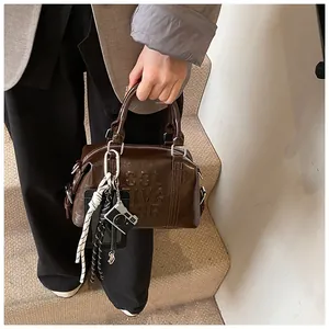Detail of dark brown faux leather bowling bag with embossed letters and camera charm