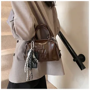 Close-up of brown wax leather bowling bag with vintage charms and textured grain details