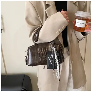 Detail of vintage brown textured bowling bag with embossed lettering and stylish charms