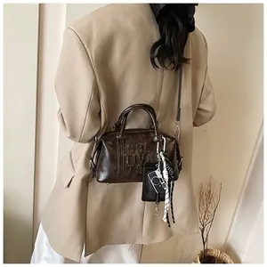 Deep brown bowling bag with embossed lettering and camera charm shown on a model