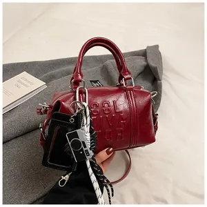 Detail of dark red bowling bag featuring embossed letters and camera charm accessory