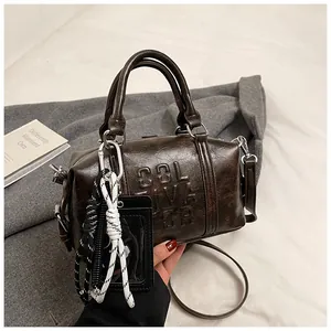 Close-up of deep brown vintage bowling bag with embossed letters and woven rope charm