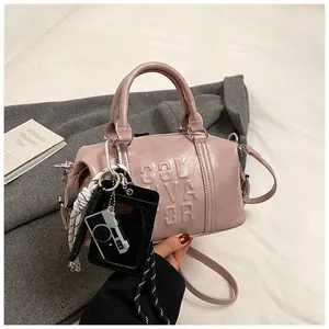 Detail of pink faux leather bowling bag featuring embossed letters and a camera charm