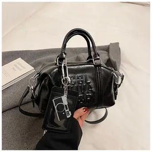 Detailed view of the black Boston bag showing COLIVA embossing and camera charm