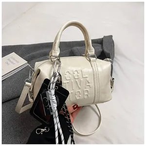 Detail of a creamy white mini bowling bag with CULTIVATOR embossed texture and charms