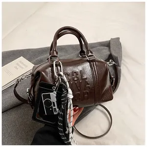 Detail of a brown polished bowling bag featuring embossed text and decorative charms