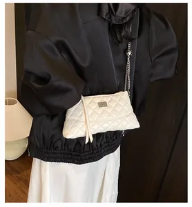 Gros plan d'un sac matelassé blanc avec fermoir argenté et pendentif en forme de cœur