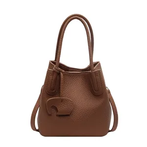 Detail of brown litchi pattern bucket bag with leather elephant charm and thin strap