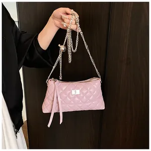 Détail d'un sac rose matelassé avec fermoir rotatif argenté et détails de pompons
