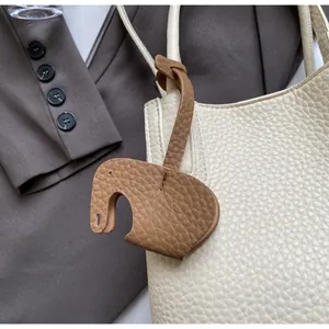 Detail of lychee pattern leather bucket bag with a cute brown elephant charm
