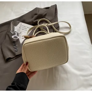 Detailed macro view of beige lychee grain texture and elegant brown leather bow on the handbag