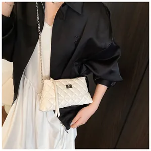 Détail du sac bandoulière matelassé crème avec fermoir argenté sur tenue en satin