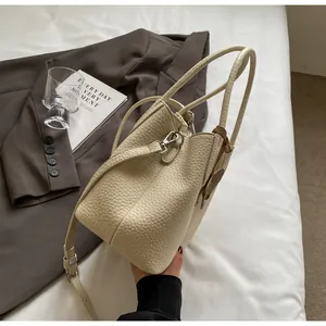 Detailed macro view of off-white lychee grain leather bucket bag with silver metal lock