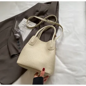 Macro detail of creamy white lychee pattern leather bucket bag with metallic hardware