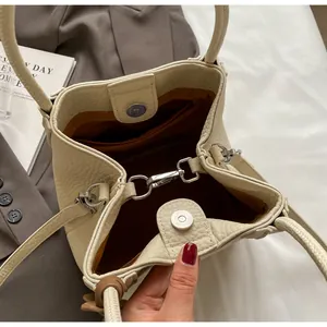 Detail view of the beige bucket bag interior showing lychee texture and magnetic closure