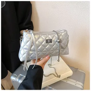 Détail du sac bandoulière argenté matelassé avec chaîne et sphère décorative en métal