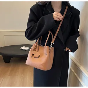 Litchi texture brown leather bucket bag with cute elephant charm and adjustable strap