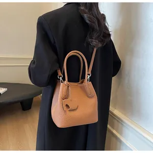Detailed texture of brown lychee leather bucket bag with an elephant charm on a black coat