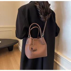 Detail showing litchi grain leather bucket bag with an elephant charm and thin strap