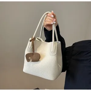Detailed view of white lychee grain leather bucket bag with elephant charm accessory