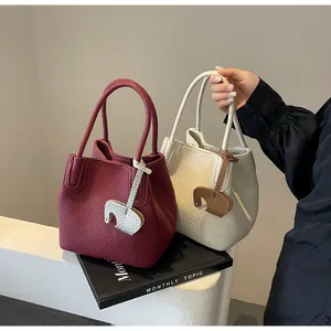 Close-up of litchi grain leather bucket bags in burgundy and beige with elephant charm