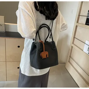Close-up of black lychee grain leather bucket bag with silver buckle and elephant charm