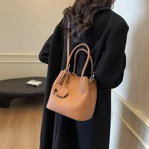 Brown litchi grain leather bucket bag with top handles and animal charm accessory