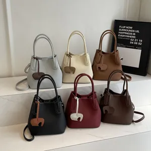 Minimalist lychee pattern bucket bags in six colors with elephant charms on white steps