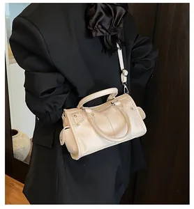 Close-up of beige pebbled leather shoulder bag with metallic rivets and motor style detail