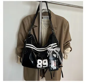Detail der schwarzen Lackleder Y2K Umhängetasche mit Nummer 89 Patch und Spitzenanhänger