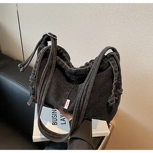 Détail du sac cabas en denim noir avec surpiqûres orange et étiquette latérale
