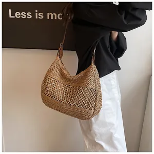 Detail of handwoven straw beach bag with hollow mesh pattern and leather shoulder strap