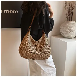 Detail of hand-woven straw hobo bag with hollow mesh pattern and leather strap