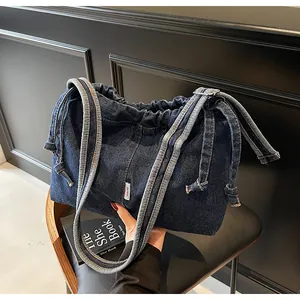 Détail macro d'un cabas en denim bleu foncé avec fermeture à cordon et bandoulière large