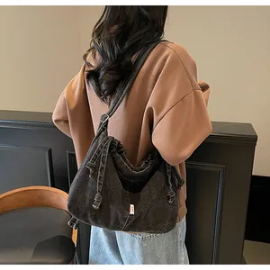 Détail d'un sac cabas en denim gris foncé avec cordon de serrage et bandoulière