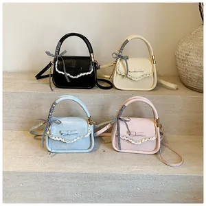 Close-up of four colorful square handbags with lace trim and ribbon handles on stone steps
