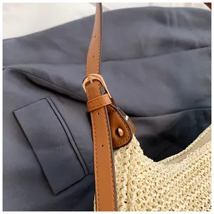 Detail of adjustable brown leather shoulder strap with gold buckle on woven beach bag