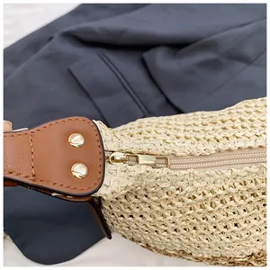 Detail of straw woven texture with a gold metal zipper and leather strap rivets