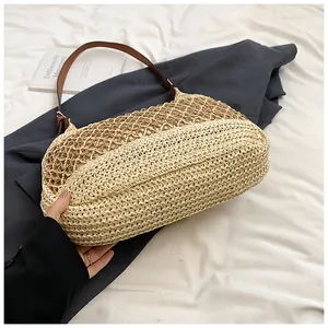 Close-up of handmade woven straw beach bag with brown leather strap and mesh texture
