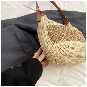 Detail of hobo straw beach bag featuring beige woven texture and brown leather strap