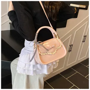 Detail of light pink crossbody bag featuring lace trim, bow, and checkered ribbon handle