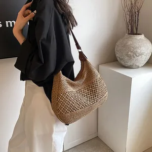 Large straw tote bag with brown leather straps and hollow mesh woven design for beach vacations