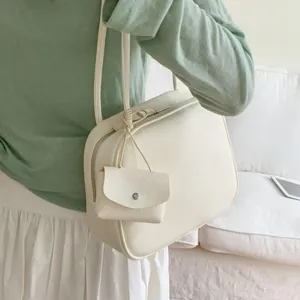 Borsa tote minimalista crema in ecopelle con portamonete indossata sulla spalla del modello