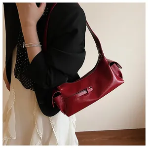 Détail d'un sac sous les aisselles en cuir rouge foncé vintage porté par un mannequin