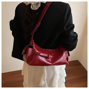 Sac à bandoulière croissant rouge brillant porté avec un blazer noir chic