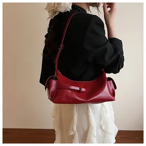 Détail d'un sac sous les aisselles rouge foncé avec poches latérales et bandoulière