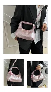Détail du sac à bandoulière rose métallisé avec logo en relief et charmant nœud décoratif