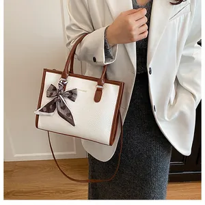 Détail du sac à main bicolore avec foulard en soie et logo imprimé doré élégant